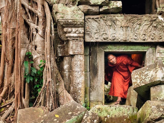 Monge explorando as ruínas de  templo no Camboja