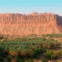 Sunset over abandoned mud houses and oasis along alulas desert mountains