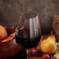 Glass of red wine served with blue cheese on dark wooden background
