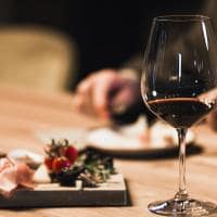 People drinking wine and eating cold cut meat in a wine cellar