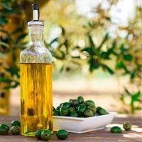 Still life with green olives and oil on table in olive grove